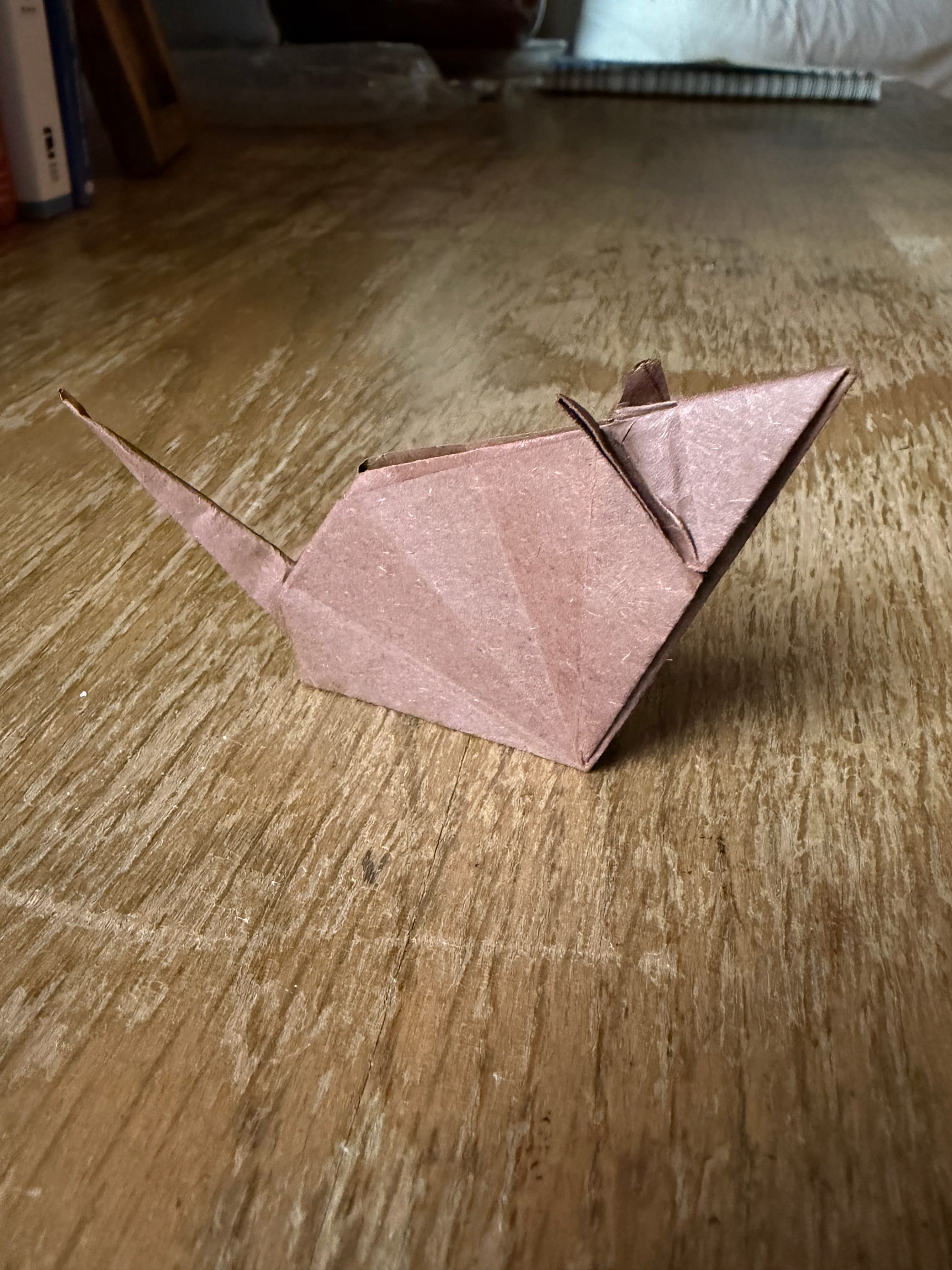 A mouse made out of brown origami paper sitting on a desk.